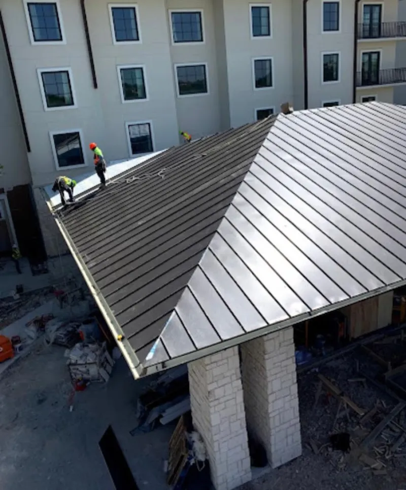 Crew installing standing seam metal roof panels on a commercial project in Newport